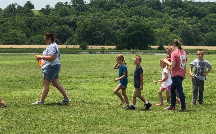 teacher and kids walking in grass 