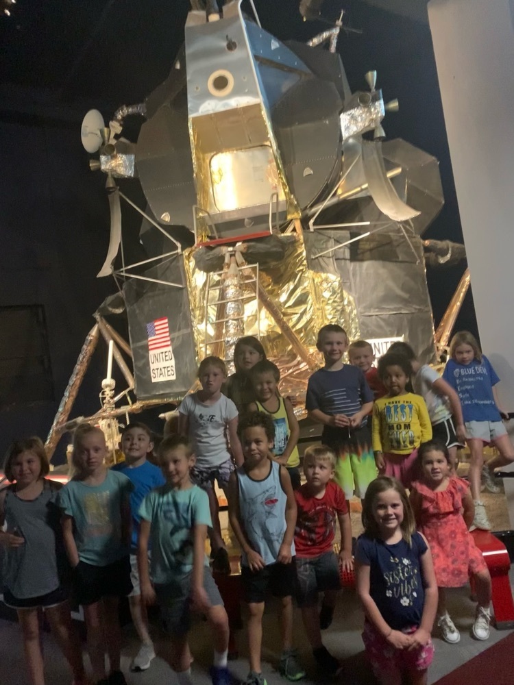 group of kids in front of rocket 